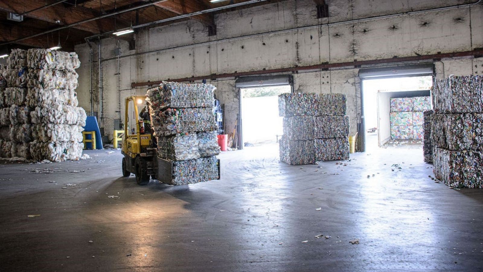 Forklift moving compressed plastic bales inside recycling warehouse facility