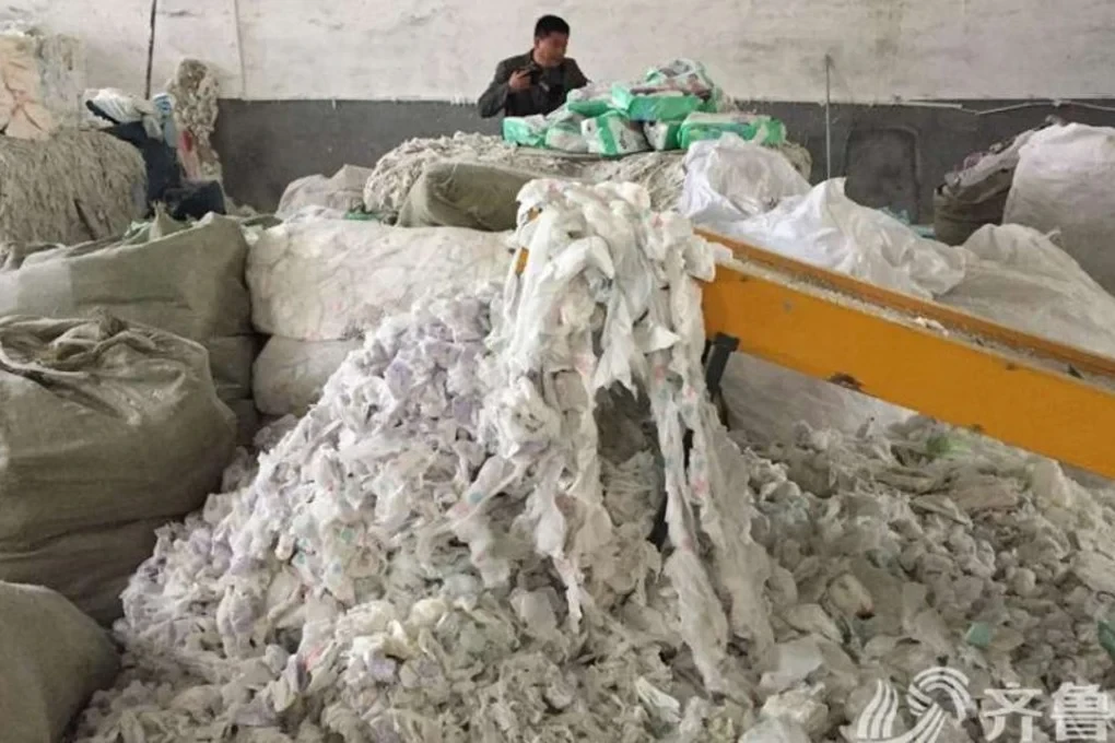 Worker sorting used diaper and hygiene waste scrap at recycling facility