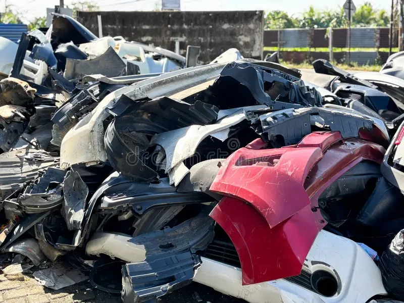 Pile of scrap automotive plastic bumpers and body parts at salvage yard
