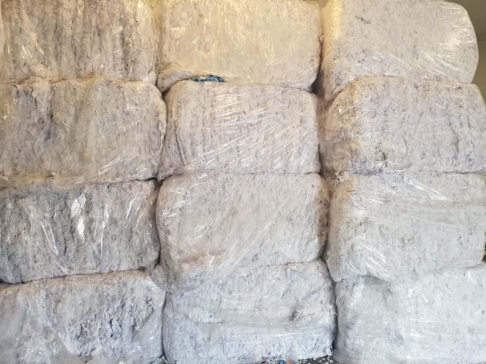 Stacked bales of white plastic film scrap in warehouse